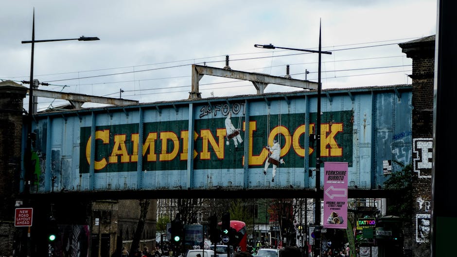A large, weathered metal railway bridge painted light blue features the words