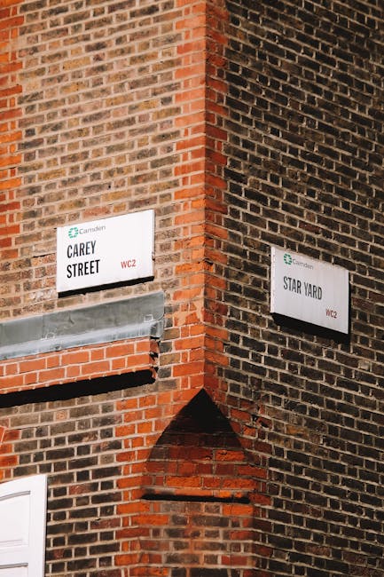 The image shows the corner of a brick building with two street signs attached to the walls, one reading 'Carey Street' and the other 'Star Yard,' indicating the intersection of the two streets. The brickwork consists of red and dark brown bricks with a rough texture, and the signs are white with black text and small green logos at the top, with additional red marking 'WC2.' Visible details include a metal lintel above a small brick archway on the Carey Street side, and the lighting appears natural, highlighting the uneven surface and aged appearance of the brick walls. The scene depicts an urban environment with no visible rubbish or waste, but it relates to waste management services by illustrating a typical city street corner where private or alternative rubbish collection services, such as those offered by House Clearance Camden, could be utilised for waste removal or clearance in the area.